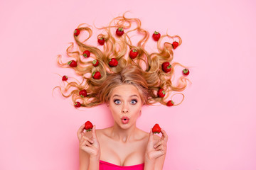 Vertical side profile top above high angle view photo beautiful she her lady lying down among strawberries long curly wavy hair arms hands hold berry wondered expression isolated pink background
