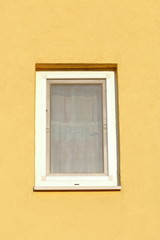 Plastic window in stucco wall. The wall is painted yellow.