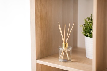 aromatherapy and home perfume concept - aroma reed diffuser on wooden shelf