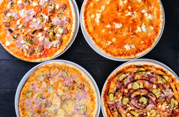 variety of mini pizzas from above on wooden table with blank space