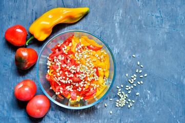 Red and yellow sweet peppers, tomatoes in a glass salad bowl on a vintage shabby gray-blue...