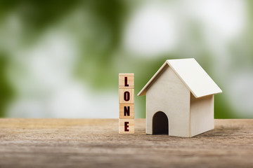 Home loan, mortgage, a property investment for future concept. A small residence house model and wooden block on wood table with nature background. A sustainable investment.