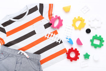 Baby clothes with plastic toys on white background
