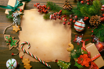 Frame with vintage paper, fir branches, cookies and Christmas decorations on dark wooden background. Letter to Santa Claus.