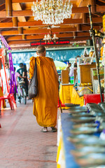 Mnich Buddyjski w tradycyjnym stroju spacerujący prz świątyni buddyjskiej w Tajlandii