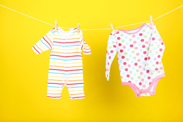 Baby clothes hanging on yellow background