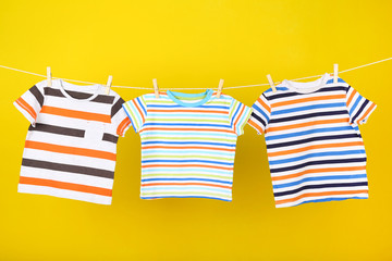 Baby clothes hanging on yellow background