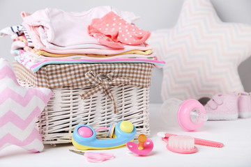 Clothes in basket with toy and baby supplies on white background