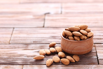 Almonds in bowl on brown wooden table