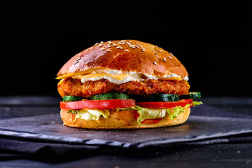 homemade burger with chicken and vegetables on a dark background