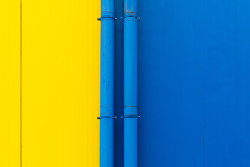 Close-up of yellow and blue surfaces separated by pipes, design background