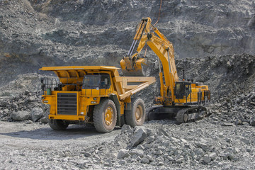Excavator loads ore into a large mining dump truck. Open pit © shubas