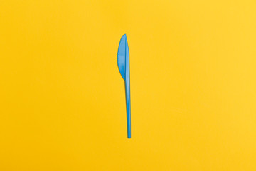 Single blue disposable knife over a yellow background.