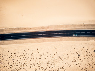 Long black asphalt road in the middle of the desert with nature and outdoors around - concept of travel and adventure in alternative beautiful scenic place - aerial view