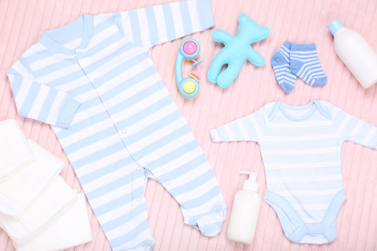 Baby clothes with toys on pink background