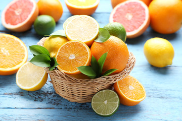 Citrus fruits with green leafs in basket on blue wooden table