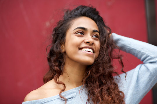 Close up beautiful young Indian woman smiling against red background