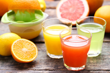 Citrus juice in glasses with fruits on grey wooden table