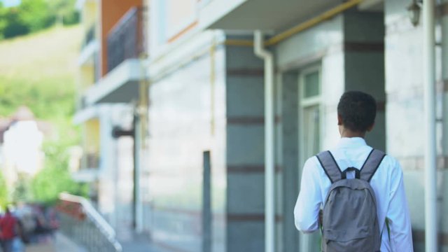African-american male student with rucksack walking to university, education