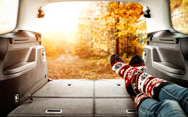 Woman legs in car interior and autumn landscape of forest 