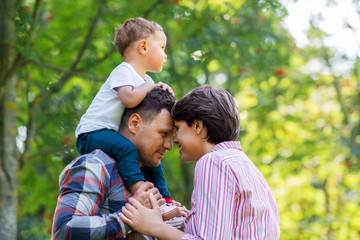 family, leisure and people concept - happy mother, father and little son at summer park