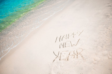 Happy New Year written in the white sand