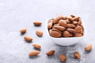 Almonds in bowl on grey wooden table