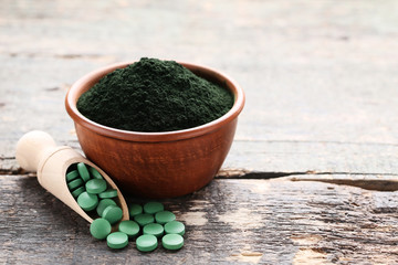 Spirulina powder and tablets on wooden table