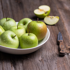 Green organic healthy apples in bowl on wooden board. Healthy food