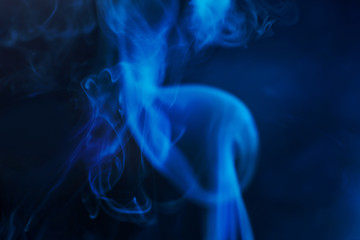 Smoke on a dark background in a mistery dark blue light. Minimalistic background concept. Copyspace.