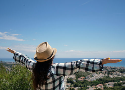 Attractive girl tourist in a hat stands on the mountain, spreading her arms wide apart, enjoying the journey, freedom © OlgaVELES