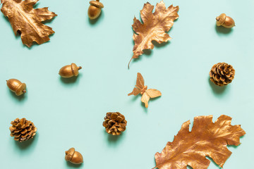 Autumn composition flat lay oak leaves acorns cones gold color on a neo-mint background