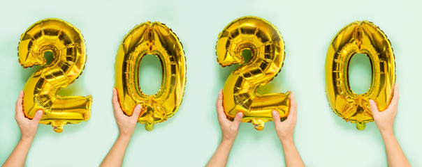 woman hands holding 2020 numbers balloons on neo-mint background. Flat lay festive decor, new year party with friends, symbol of 2020 gold color