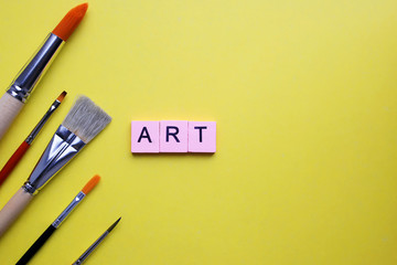 Paint brushes and word art, on yellow background
