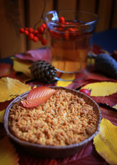 Apple crumble on a background of autumn leaves. Autumn fruits cake.