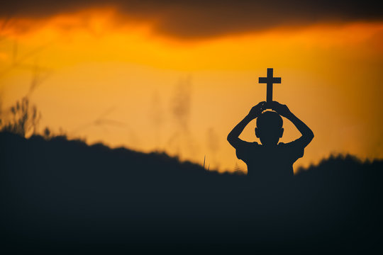 Children holding christian cross on head with sunset background,christian silhouette concept.