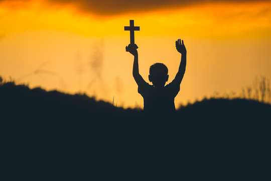 Children holding christian cross and worship with sunset background,christian silhouette concept.