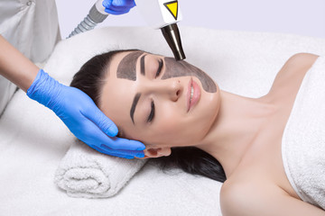 A cosmetologist is making carbon face peeling procedure in a beauty salon. Hardware cosmetology...