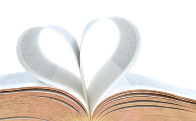 Close crop of a bible with pages making a heart. Isolated on white. 
