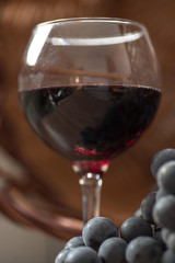 A glass of fragrant red wine and bunches of blue grapes