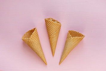 Three empty waffle cones on a pink background. Minimalism. Flat lay.