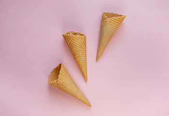 Three empty waffle cones on a pink background. Minimalism. Flat lay.