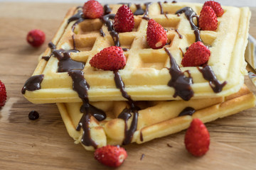 Two Viennese waffles with chocolate and berries on a wooden Board