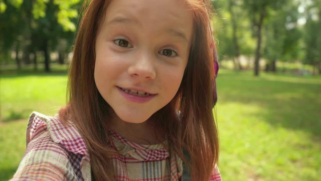 cute redhead child talking at camera and waving hand