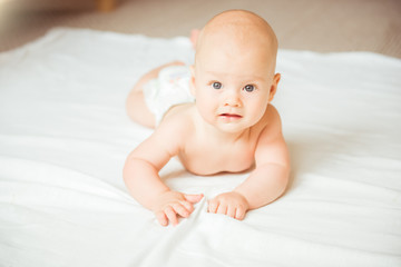 Adorable baby boy lying on a white bed