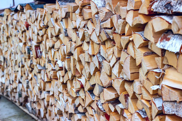 Birch firewood in a woodpile in a village. Abstract background.