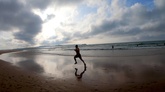Athlete silhouette of runner running on beach