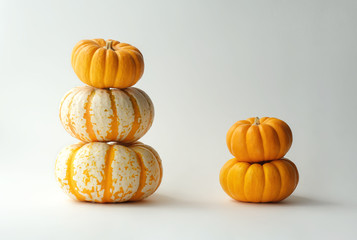 Stacked pumpkins on a white background, Orange and Tiger pumpkins pyramids.