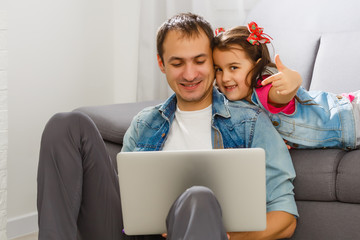 Father watching his cute daughters using the laptop computer