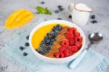 Vegetarian health food. Mango and orange smoothie bowl with fresh berries and nuts.